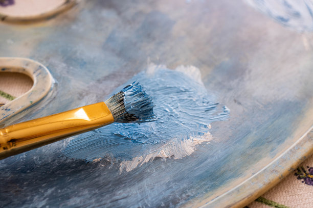 一支涂有蓝色油彩的刷子放在调色板上。图片下载