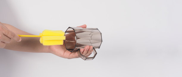 清洁和洗碗的概念。在白色背景上的男子洗手喝玻璃。用黄色软海绵棒清洗饮用玻璃。用海绵刷清洗杯子。新冠肺炎时代的消毒卫生图片下载