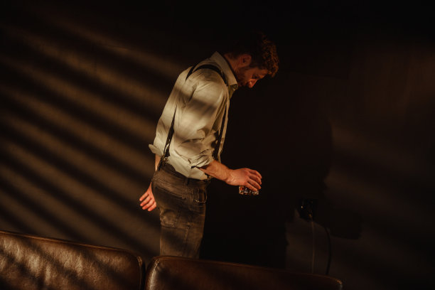 一个男人喝醉了，手里拿着一杯威士忌，在房间里徘徊的氛围照片图片下载