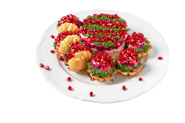 宴会自助餐的食物。石榴沙拉配上填充的泡芙饼和馅饼放在盘子里，白色的背景孤立图片下载