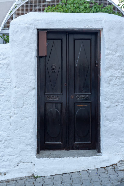 白色石墙上暗色木门，铁质把手。垂直的照片。图片下载