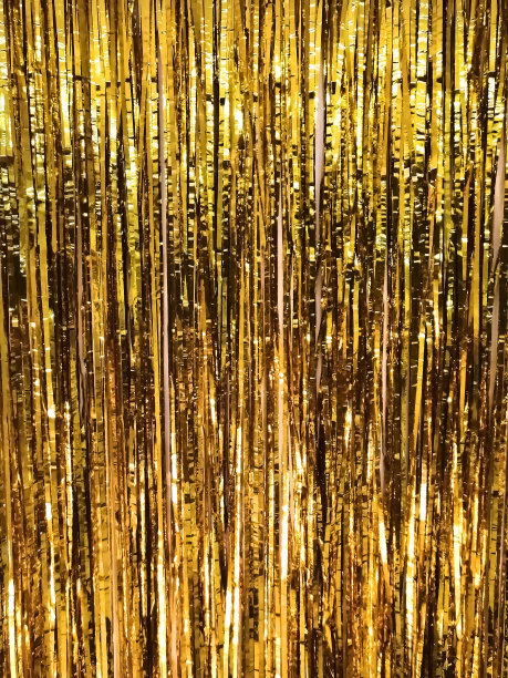 节日闪亮的金箔流苏，金色的背景与选择性的焦点。图片下载
