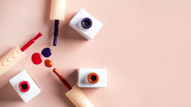 不同颜色的刷子明亮的指甲油瓶子在浅粉色的背景。副本的空间。图片下载