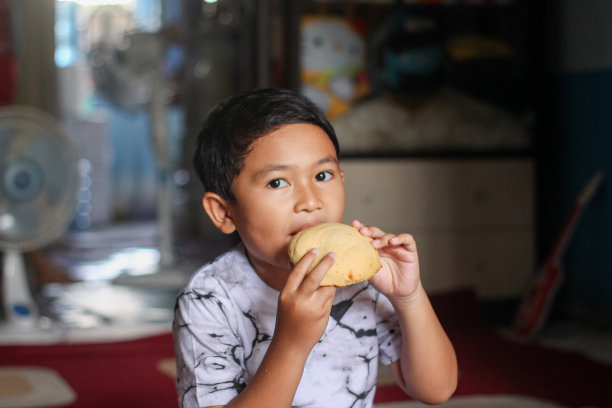 男孩坐在家里吃面包图片下载