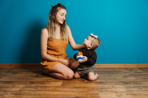 婴儿时尚，选择服装和配饰。妈妈在家里给蹒跚学步的小女孩穿衣服。妈妈和小时尚宝贝女儿图片下载