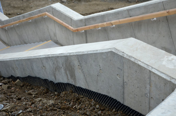 从手柄底部是一个凹形LED带黄色的灯。隐藏的内置灯显示了一个男人的手。带有挡土墙的混凝土楼梯贯穿斜坡的地形图片下载