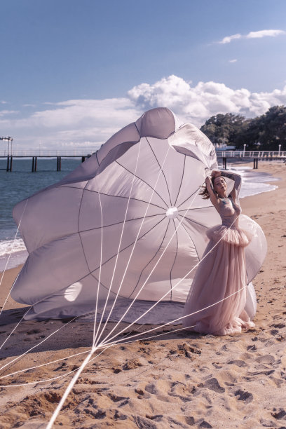 沙滩上那个带着白色降落伞的漂亮女人图片下载