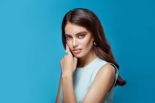 正面肖像一个年轻的女人穿着浅蓝色的衣服，看着相机，在蓝色的背景。图片下载