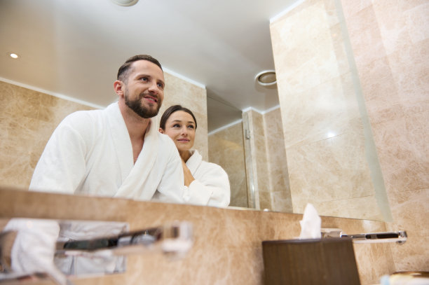 美丽的年轻情侣，新婚夫妇在他们的蜜月享受在一起，拥抱在一起站在浴室里，看着镜子里的自己。爱,感情,温柔。图片下载