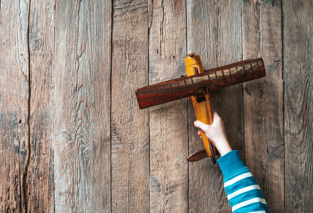 一个男孩手里拿着玩具木飞机。图片下载