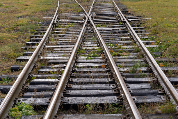 这张照片是一条木铁轨和绿色的草地。火车与交通概念图片下载