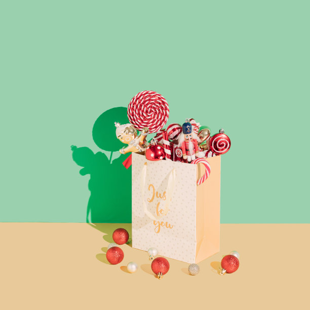 圣诞装饰品从礼品袋里掉出来，放在金色和浅绿色的背景上。圣诞节和新年假期的概念。图片下载