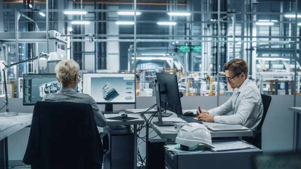 汽车工程师团队在汽车装配工厂的现代办公室中使用台式电脑。在汽车厂与同事一起开发电动发动机零件。图片下载