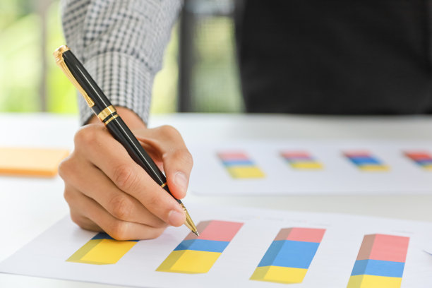 商业和规划概念。闭幕式上的亚洲商人手拿钢笔在条形图文件纸上写字。图片下载