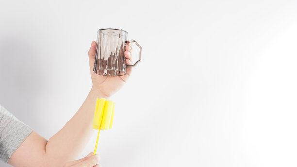 清洁和洗碗的概念。在白色背景上的男子洗手喝玻璃。用黄色软海绵棒清洗饮用玻璃。用海绵刷清洗杯子。新冠肺炎时代的消毒卫生图片下载