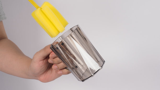 清洁和洗碗的概念。在白色背景上的男子洗手喝玻璃。用黄色软海绵棒清洗饮用玻璃。用海绵刷清洗杯子。新冠肺炎时代的消毒卫生图片下载