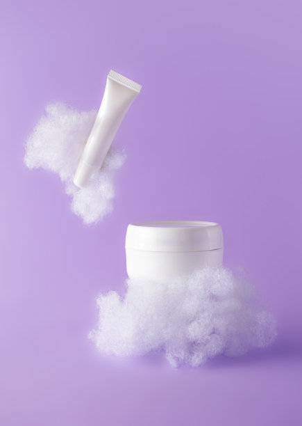 面霜和润唇膏，紫色背景上有蓬松的云朵。概念护理与敏感皮肤。创造性的静物照片，垂直。美容产品模板模型图片下载