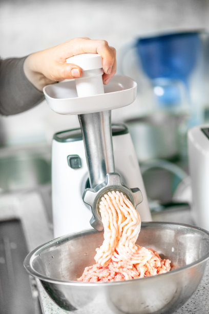 在厨房用磨碎机准备肉末的妇女图片下载