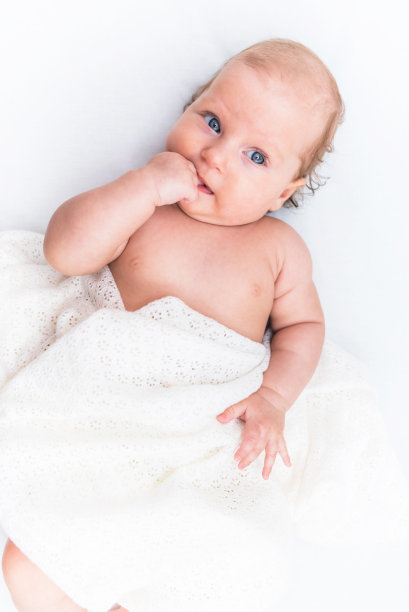 快乐的女婴躺在她房间的白色床单上图片下载