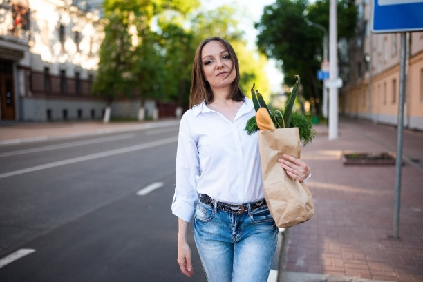 一个漂亮的女孩拿着一个装着杂货的纸袋。图片下载
