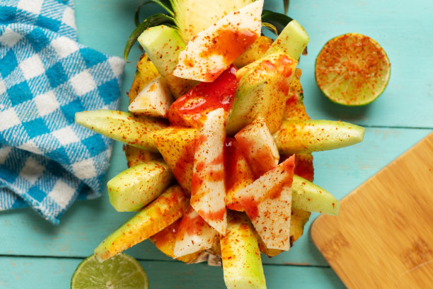 黄瓜，豆薯，菠萝，辣椒粉和chamoy酱在绿松石背景上。墨西哥小吃图片下载