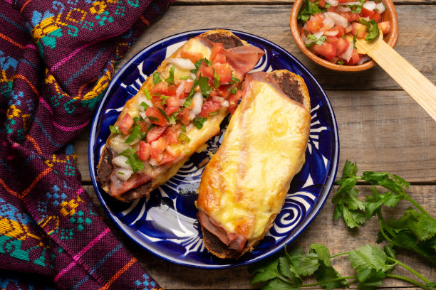 Molletes火腿，炸豆和融化的奶酪在灰色的背景上。墨西哥食物图片下载