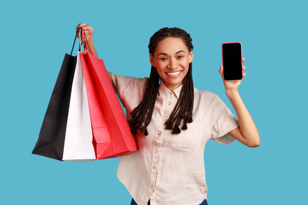 留着长发绺的女人手里拿着购物袋，手里拿着空着的手机做广告。图片下载