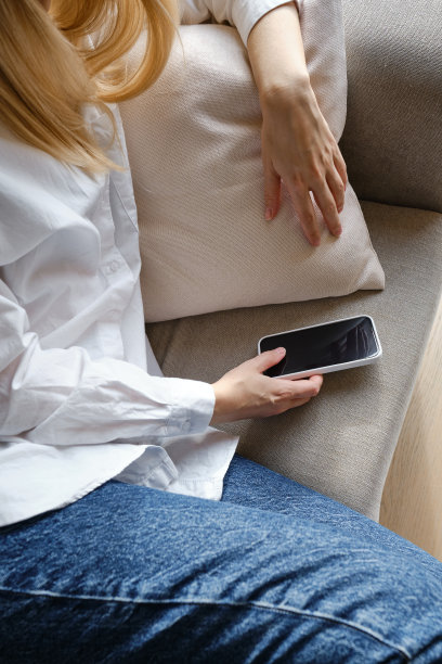 躺在舒适的床上，手里拿着智能手机，睡觉前或起床后查看社交网络账号。小玩意上瘾。女人用手机发短信图片下载