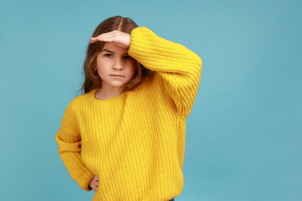 爱管闲事的认真的小女孩用手捂着眼睛，望着远方，观察着地平线。图片下载
