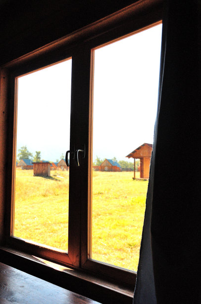 从房间的窗户可以看到一片阳光明媚的草地和其他房子。图片下载