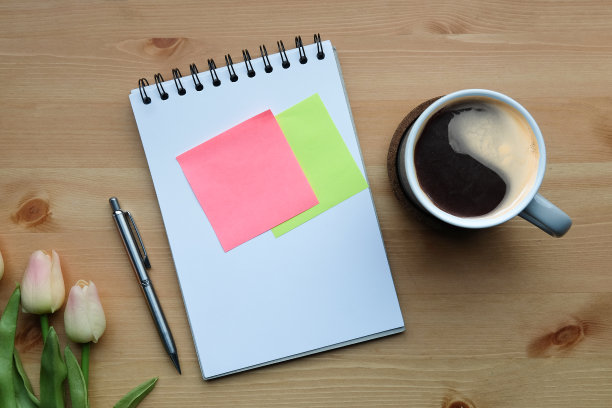 上面的观点咖啡杯，记事本，便利贴和粉红色的郁金香在木桌上。图片下载