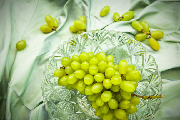 绿葡萄在水晶碗上泰国丝绸织物，自然光背景图片下载