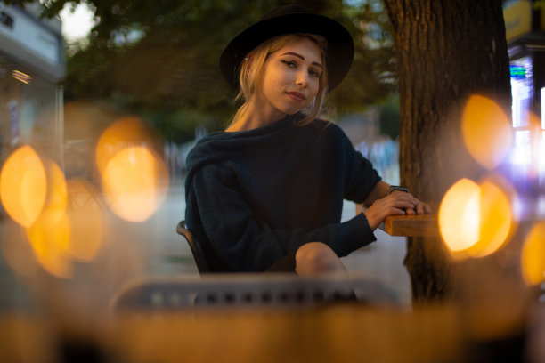 美丽的金发女人肖像温柔的侧道时尚风格的布在天井咖啡桌公园室外空间以散景黄色照明照明前景图片下载