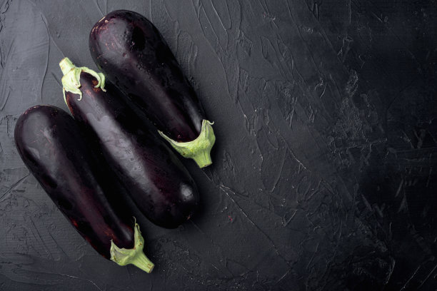 新鲜的有机茄子，在黑色的石头背景，顶视图平铺，与复制空间的文字图片下载