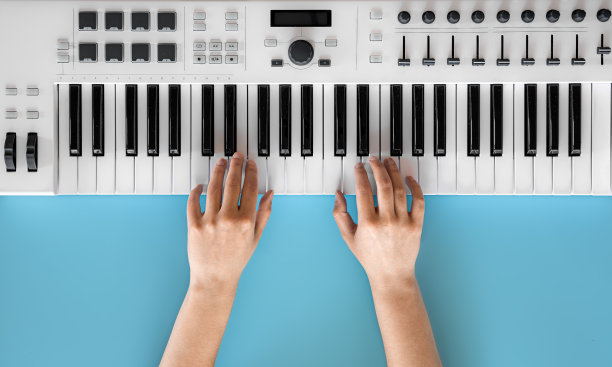 女性的手在蓝色背景下弹奏音乐键，俯视图。图片下载