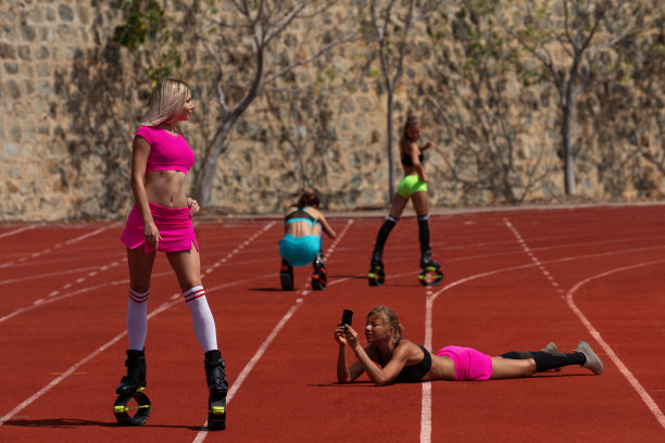 四个女孩穿着kangoo跳靴做运动，其中两个摆姿势喝着水，其他人在拍她们的照片图片下载