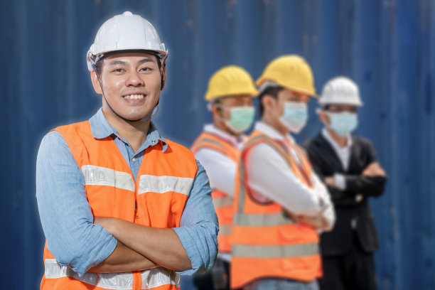 工厂工程师亚洲人站的信心。群男工人戴着口罩站在集装箱前墙货物。图片下载
