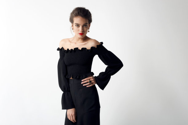 正面肖像，化妆和发型的女人，穿着黑色的衣服，裸露的肩膀，在白色的背景。图片下载
