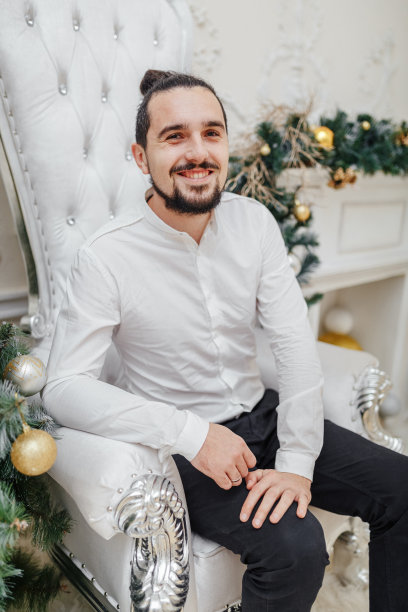 一个英俊的小伙子坐在新年派对的椅子上图片下载