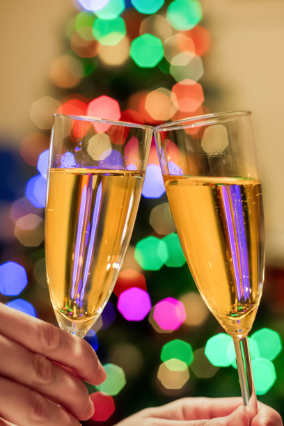 模糊的圣诞树和两个装满汽酒香槟的玻璃杯。新年的概念图片下载