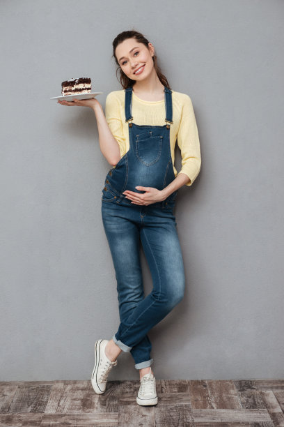 幸福的孕妇捧着甜蜜的蛋糕。图片下载