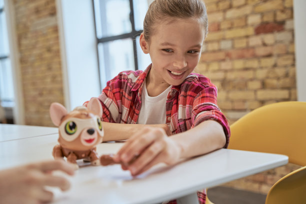 迷人的小女孩坐在桌旁，检查技术玩具和微笑，花时间在工程俱乐部图片下载