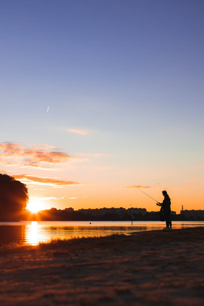 河岸边垂钓人孤独气氛周末活动美丽如画日落黄昏灯光，垂直摄影，无聚焦剪影概念的人类图片下载