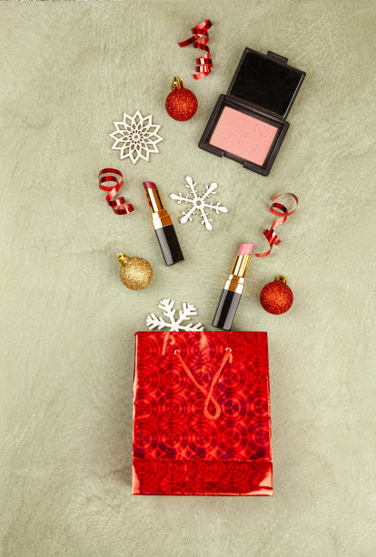 圣诞平铺，米色背景上有一个礼品袋，里面装着化妆品。从以上观点。图片下载