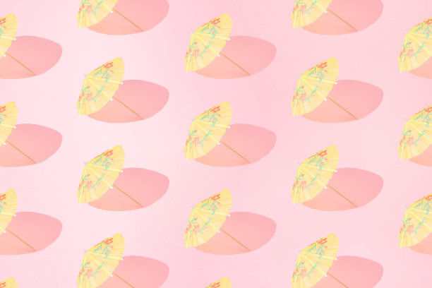 安排黄色的夏日沙滩伞在粉红色柔和的背景。模式。图片下载