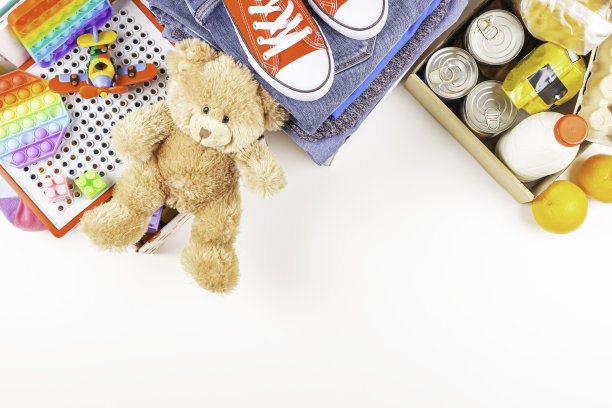 捐赠、慈善的概念。白色桌上放着食物捐赠箱，里面有食品杂货、衣物和儿童玩具。俯视图，复制空间图片下载