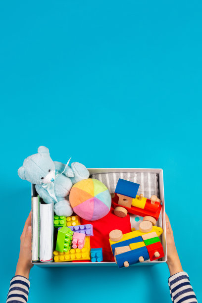 捐赠的概念。孩子们的手与捐赠箱，衣服，书籍和玩具在浅蓝色的背景。俯视图图片下载