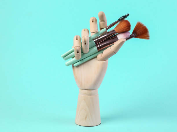 木制的手握着蓝色背景上的化妆刷图片下载