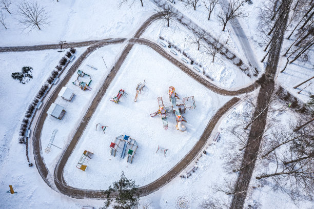 空中俯瞰空空如也的积雪覆盖儿童游乐场在阳光明媚的早晨在冬天的时间图片下载