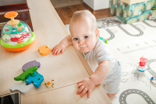 婴儿在地板上玩有教育意义的玩具，摇铃和长牙玩具。8个月的婴儿会爬…图片下载